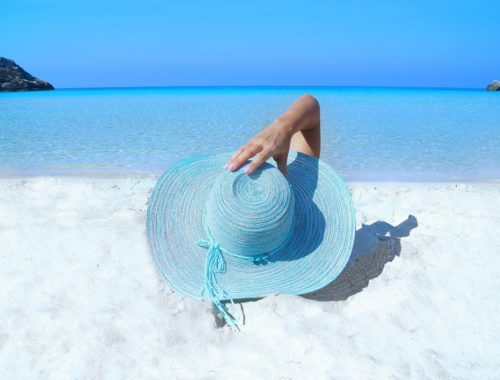 femme à la plage portant un chapeau et prenant le soleil.